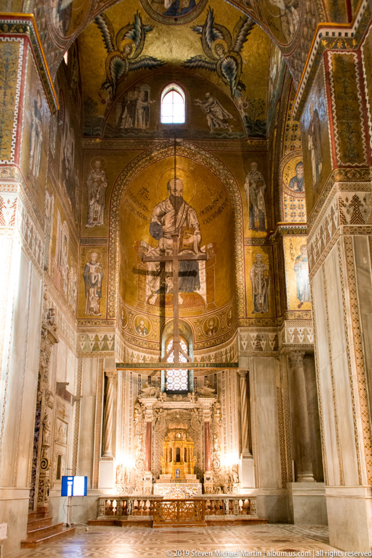 A gold mosaic fills the apse above the distant altar, framed by decorated walls and arches.