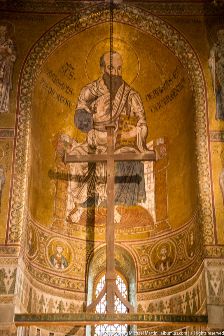 A haloed bearded figure holds a book in a gold-ground mosaic with surrounding inscriptions.