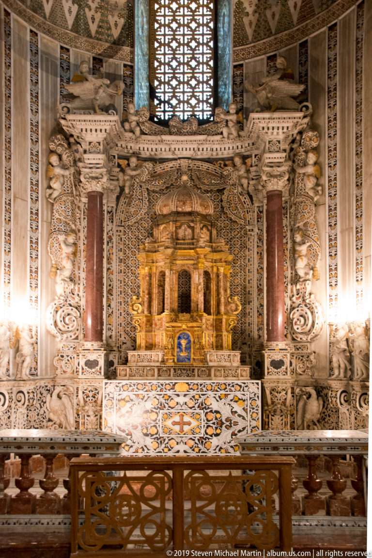 A wide cathedral nave leads between tall columns toward an ornate sanctuary and mosaics.
