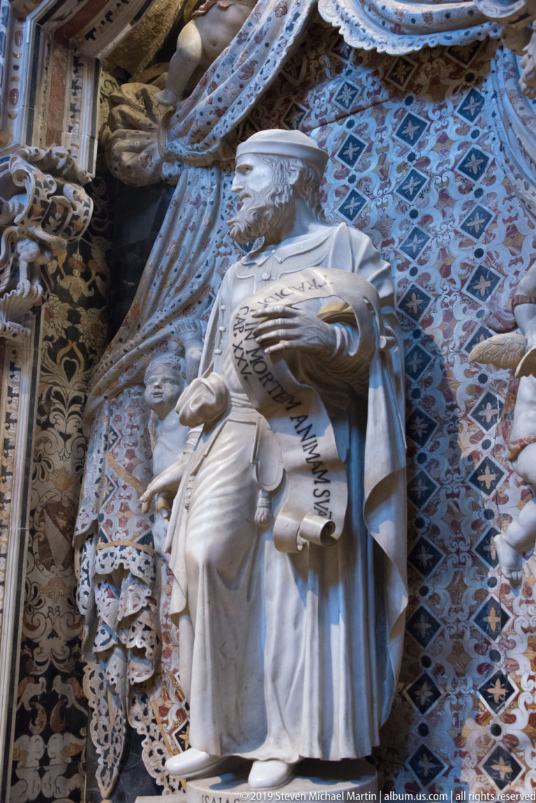 Isaiah holds an inscribed scroll before a blue and gold patterned niche.
