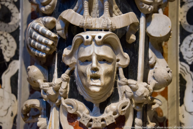 Daniel’s marble face and hands holding a scroll fill a close view against patterned inlay.