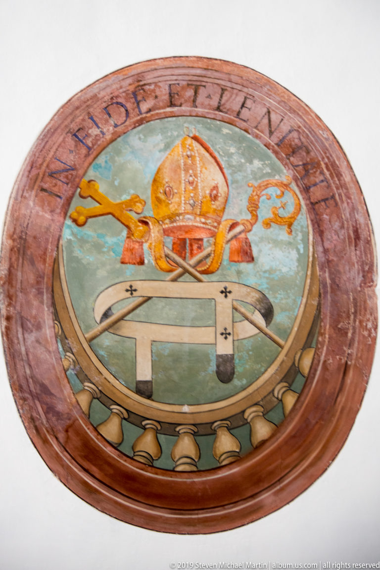 A mosaic medallion shows a papal tiara and crossed keys on a pale blue field.