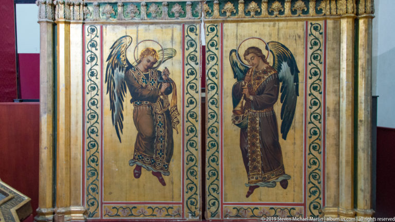 Two haloed winged figures stand in separate mosaic panels framed by patterned vertical borders.