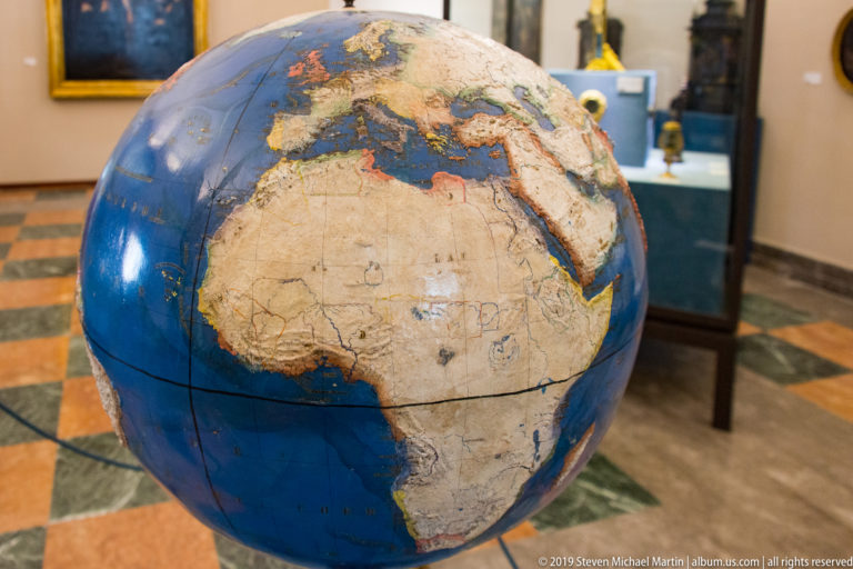 A blue globe shows Europe and Africa in the foreground of an indoor display space.