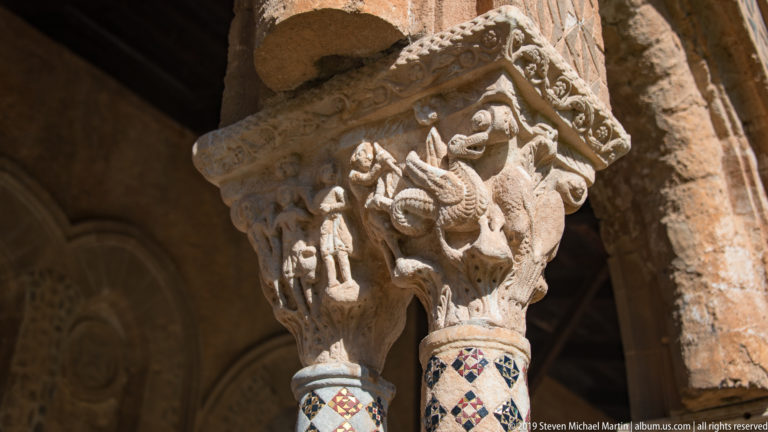Carved human figures sit above two columns with contrasting colored geometric inlay.