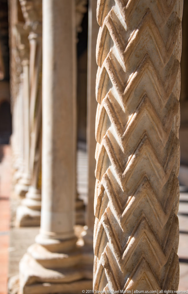 A close-up of a stone column shaft carved with repeated zigzag bands.