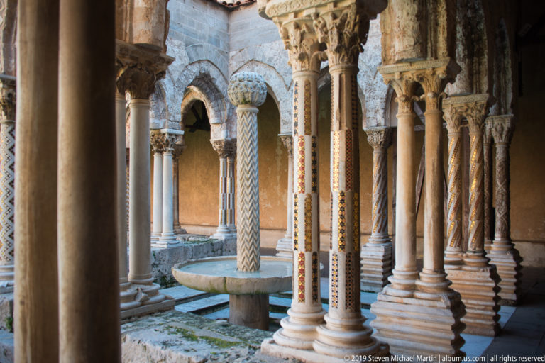Decorated columns and arches surround a circular fountain in Monreale’s cloister.