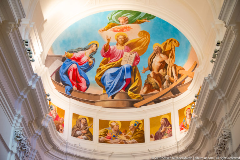 Curved apse mural with enthroned Christ, the Virgin and other sacred figures above a lower band of smaller saint paintings.