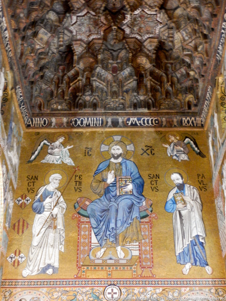 Gold mosaic of enthroned Christ flanked by Saints Peter and Paul beneath the dark carved wooden ceiling.