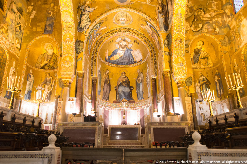 Wide frontal view of the Palatine Chapel sanctuary covered in gold mosaics, with Christ above the Virgin and Child.