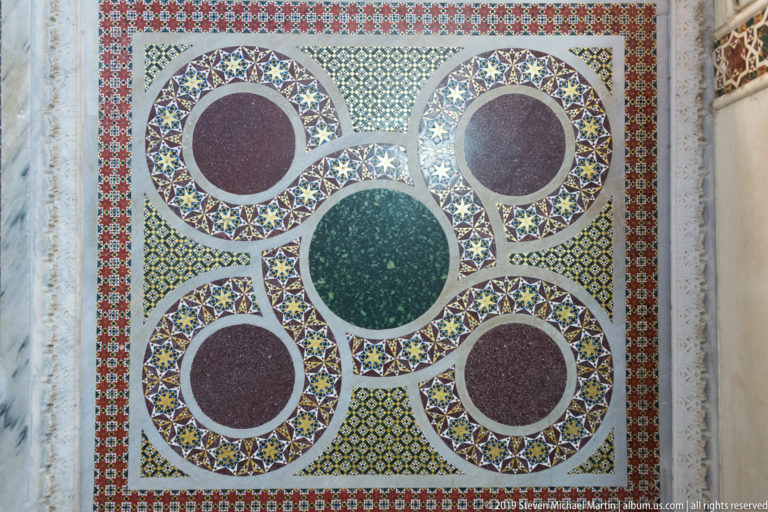 Polychrome geometric pavement with circular stone inlays.