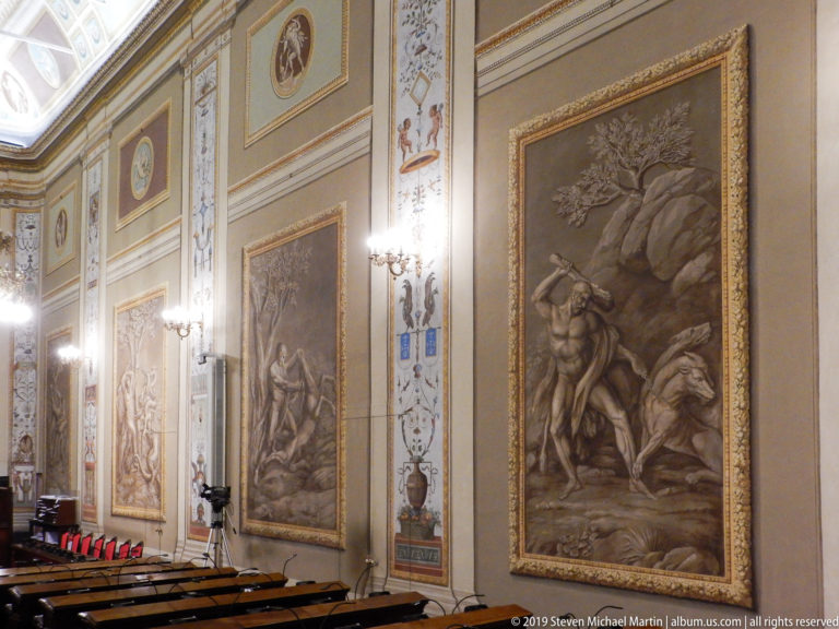 Large monochrome figural wall panels in a formal chamber.