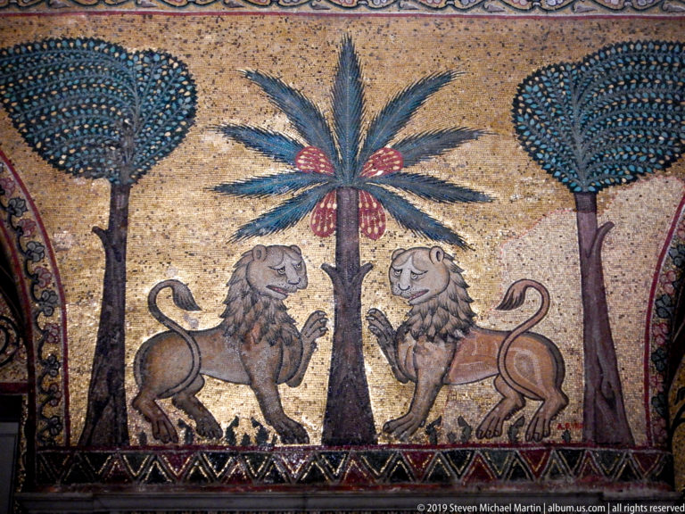 Paired lions flanking a fruiting palm in a gold-ground mosaic.