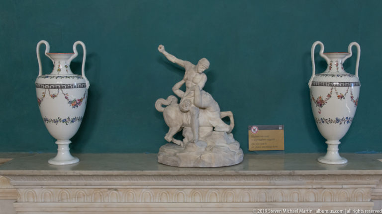 Marble figural group flanked by matching porcelain vases.