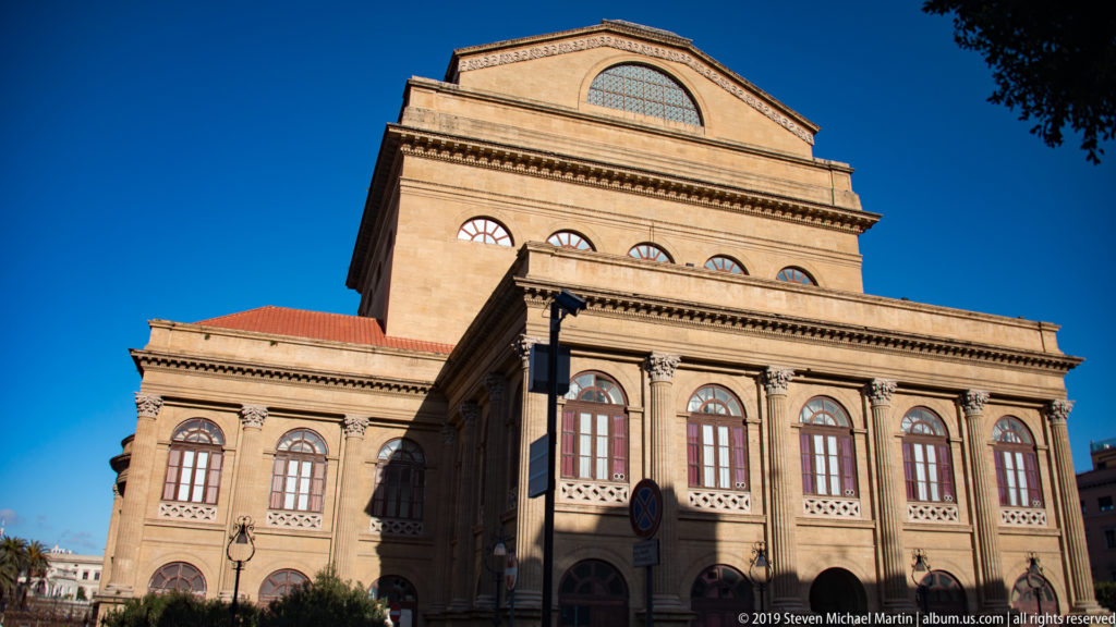 Side exterior of Teatro Massimo with arched windows, classical cornices, and the tall rectangular stage-house volume.