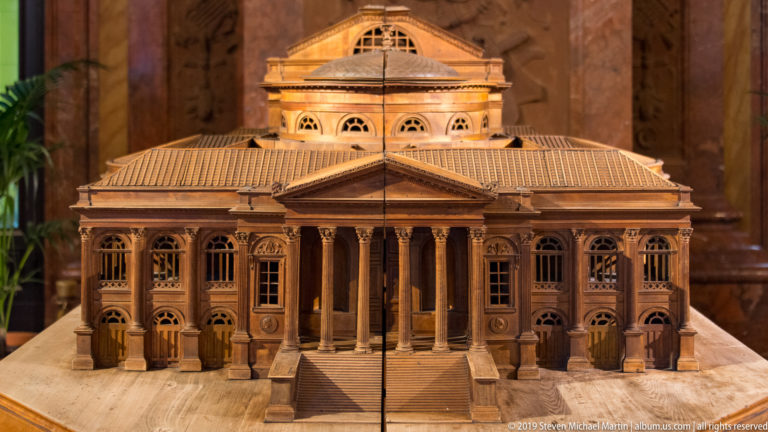 Front view of a wooden Teatro Massimo model with broad steps, columned portico, pediment, and symmetrical wings.