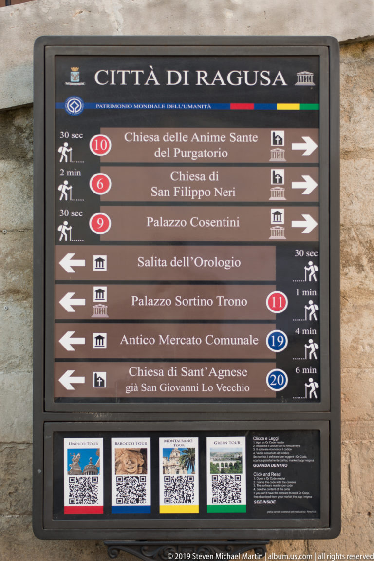 Città di Ragusa directional sign listing churches, palaces, the clock stairway, and old municipal market.