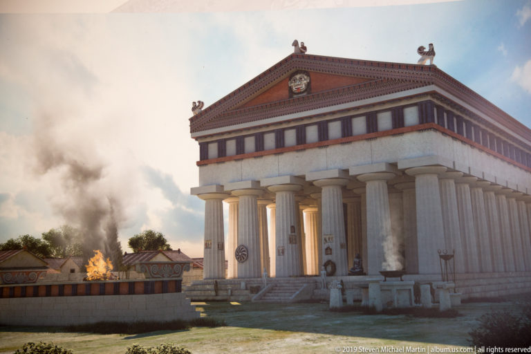 Illustrated classical temple with tall columns, painted roof trim, figures, smoke, and a ritual fire in the foreground.