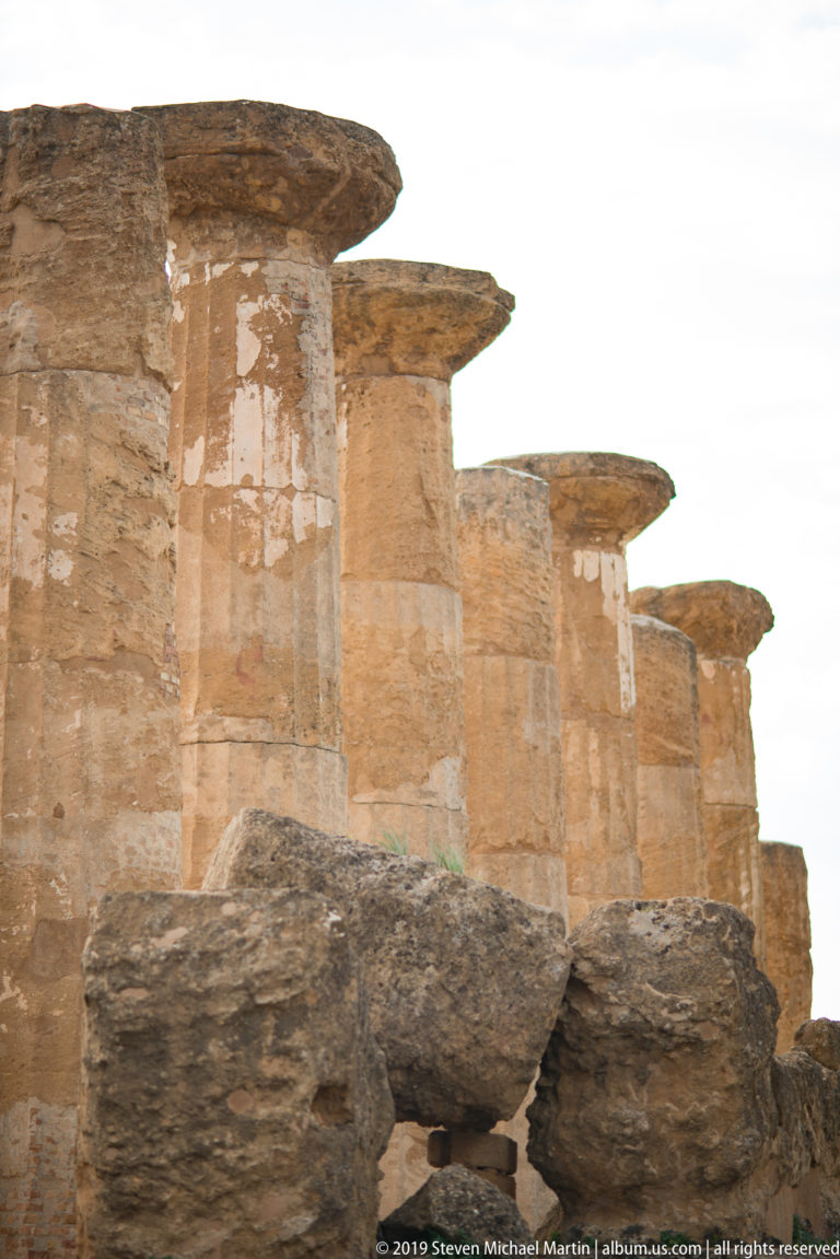 Close low-angle view of weathered Doric columns and projecting capitals above rough stone blocks.