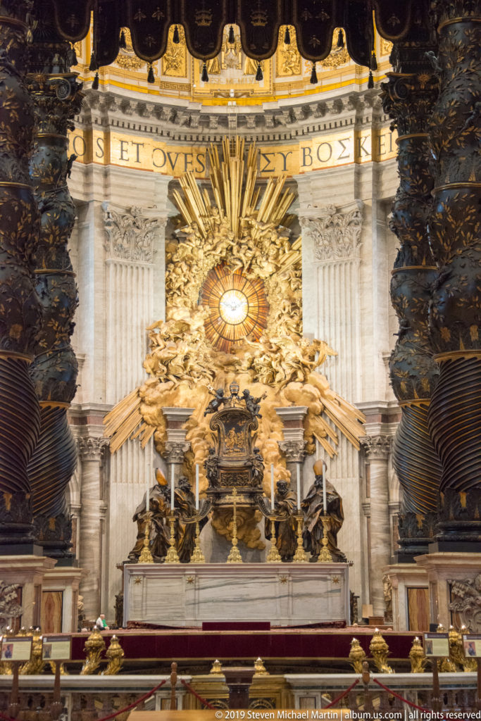 The Altar of the Chair of Saint Peter with gilded sculpture surrounding the glowing oval Holy Spirit window in the apse.