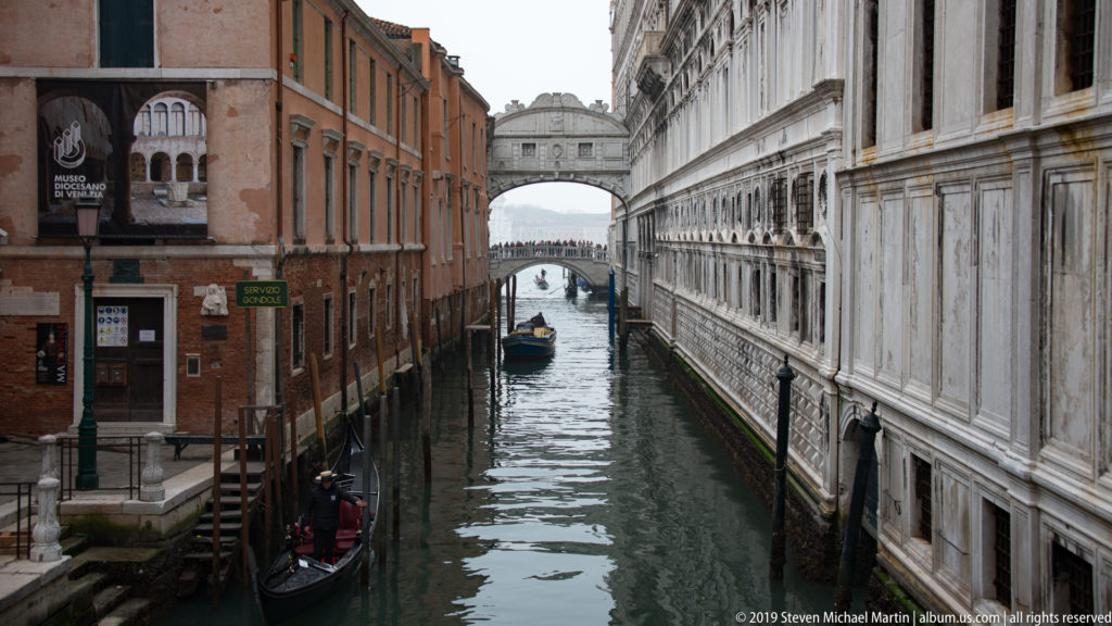 Bridge of Sighs crosses the narrow Rio di Palazzo between the Doge's Palace and a brick building, with gondolas below.