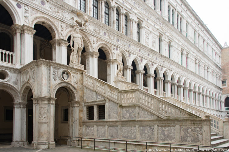 Oblique view of the Scala dei Giganti rising beneath the arcaded courtyard façade of the Palazzo Ducale.