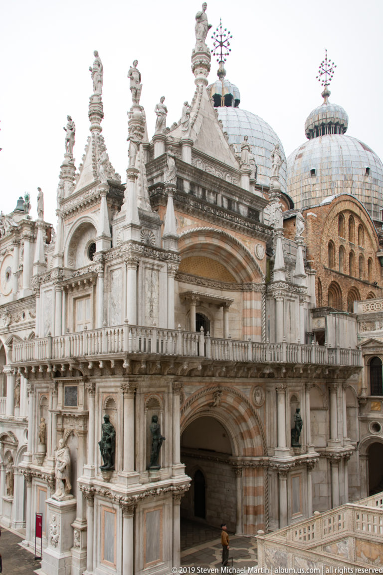 Sculpted Arco Foscari in the Palazzo Ducale courtyard with the domes of St Mark’s Basilica rising behind.