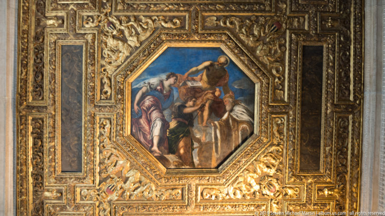 Octagonal multi-figure painting set within a dark coffered ceiling densely framed by gilded carving and narrow decorative panels.