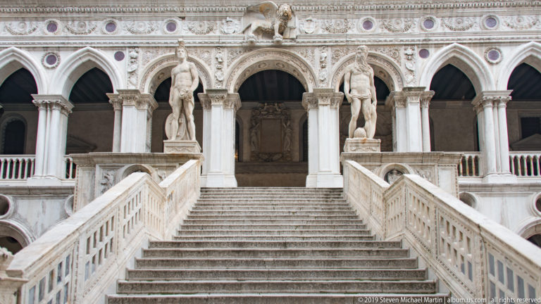 Giants’ Staircase rising between carved balustrades toward Sansovino’s statues of Mars and Neptune at the upper landing.