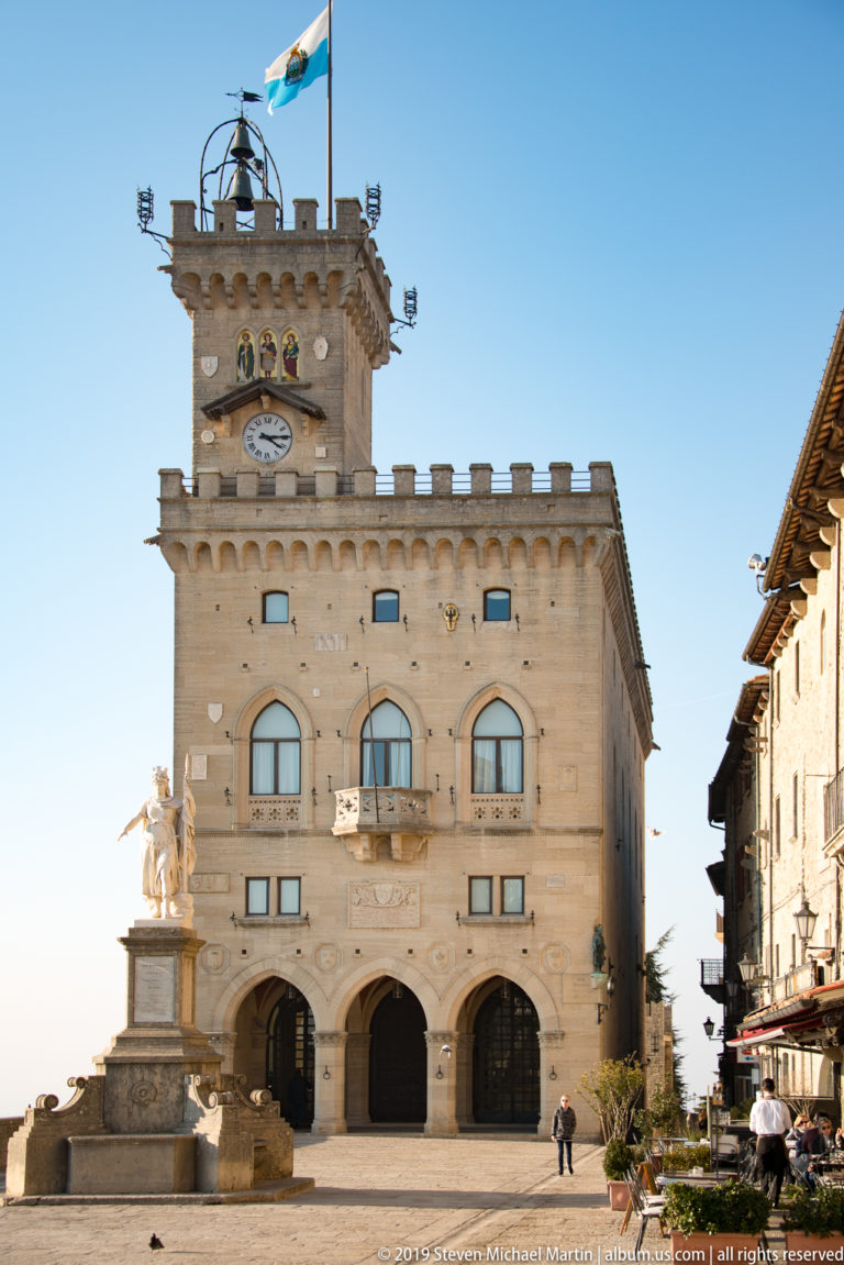 Palazzo Pubblico with clock tower and flag facing Piazza della Libertà, with the Statue of Liberty at left.