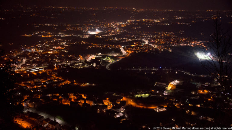 Expansive night panorama of city lights, roads, and dark hills across the plain below Monte Titano.