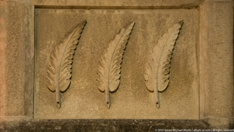 Rectangular stone panel carved with three vertical feather- or quill-shaped motifs in low relief.