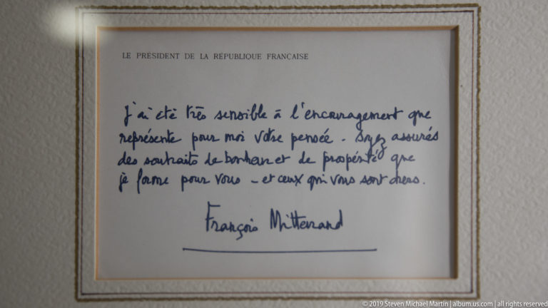 Framed handwritten French note in blue ink on presidential stationery, signed François Mitterrand.