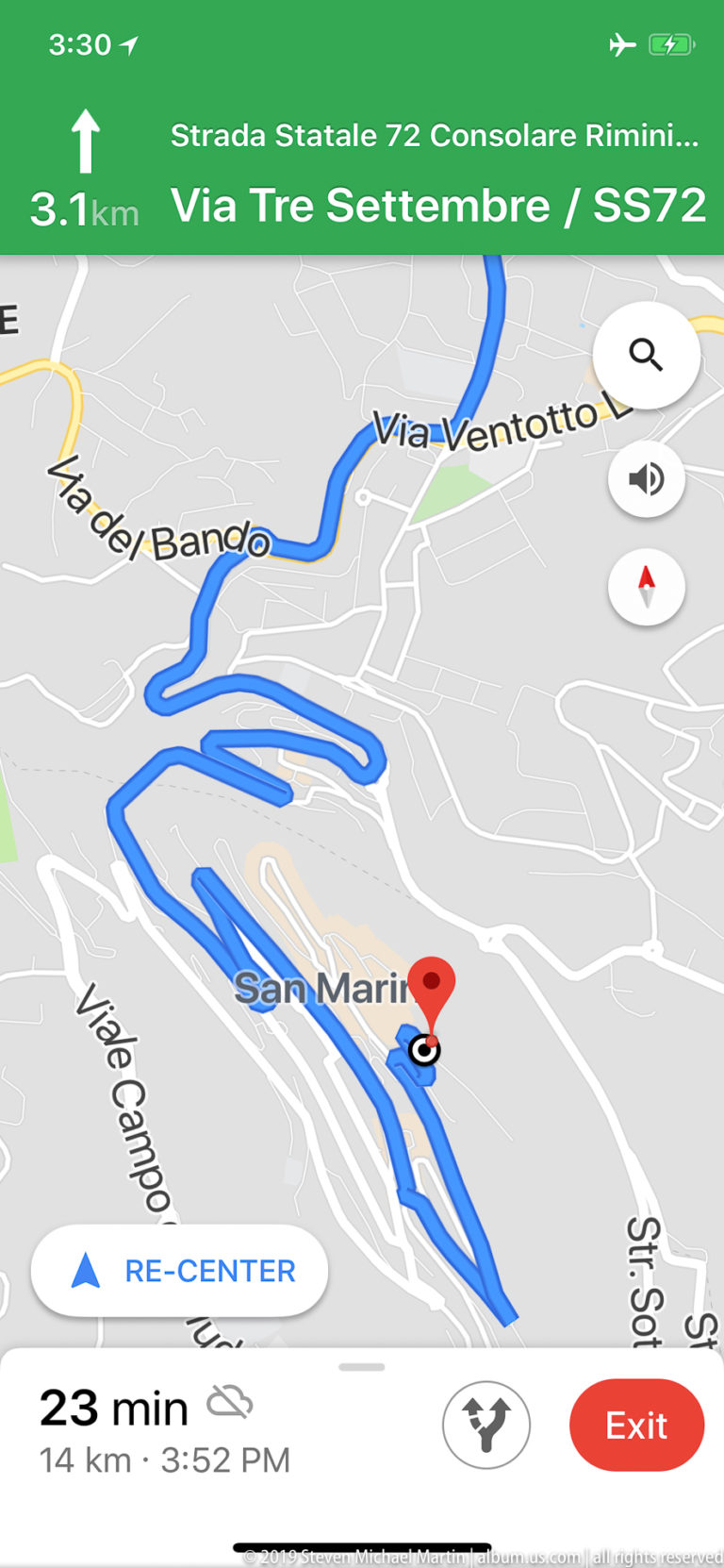 Navigation screen showing a blue driving route with tight switchbacks around San Marino and a green directional banner.