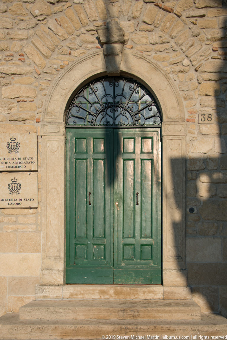 Green double doors beneath an arched fanlight with ironwork, set in a stone façade marked number 138.