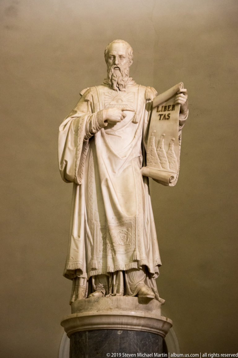 Adamo Tadolini’s marble Saint Marinus holding a mason’s tool and LIBERTAS tablet behind the Basilica of Saint Marinus high altar.