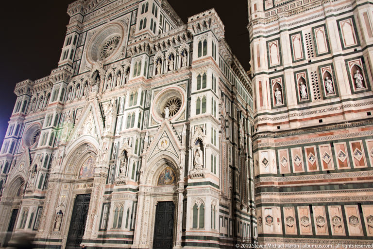 Oblique illuminated view along Florence Cathedral’s façade with the lower wall of Giotto’s Campanile at right.