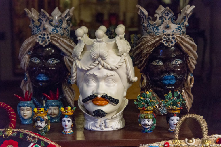 Colorful ceramic head sculptures and small face-shaped vessels crowded together in a Florence shop display.