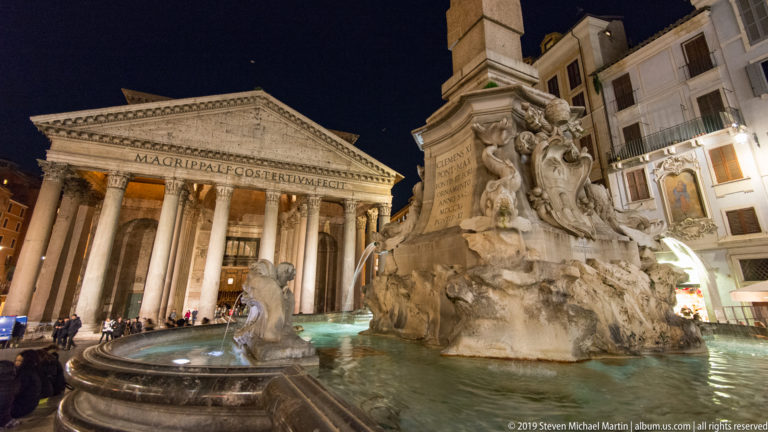 Fontana del Pantheon and obelisk in the foreground with the illuminated Pantheon portico directly behind at night.