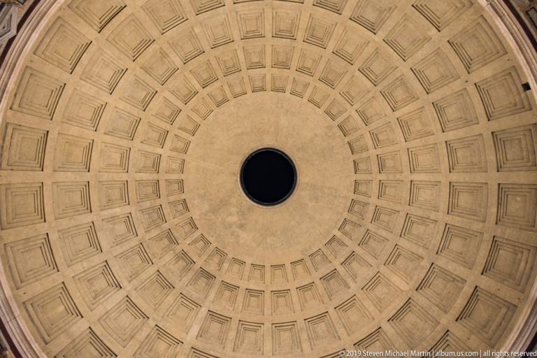 Centered upward view of the Pantheon’s pale coffered dome, with concentric recessed panels surrounding the dark circular oculus.
