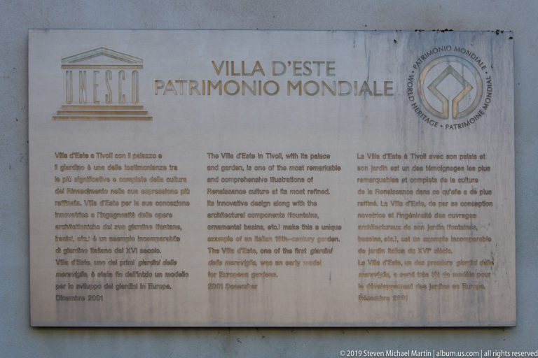 Stone UNESCO plaque for Villa d’Este with emblem and explanatory text in Italian, English, and French.