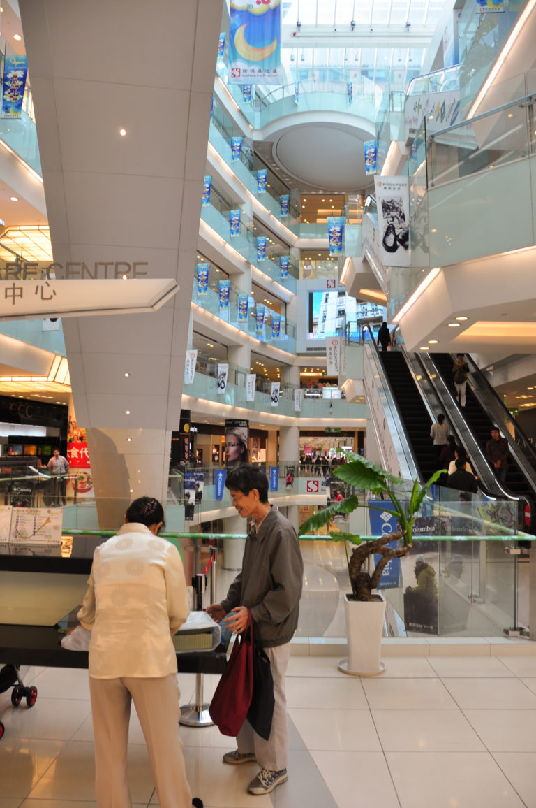 Bright multi-level atrium of a modern Beijing department store with escalators and open balconies lined with shops.
