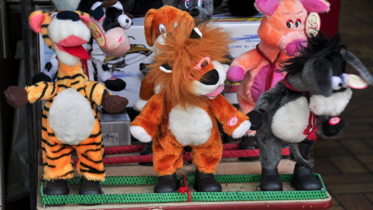 Coin-operated plush animal toys on a motorized platform in a Beijing shop display.