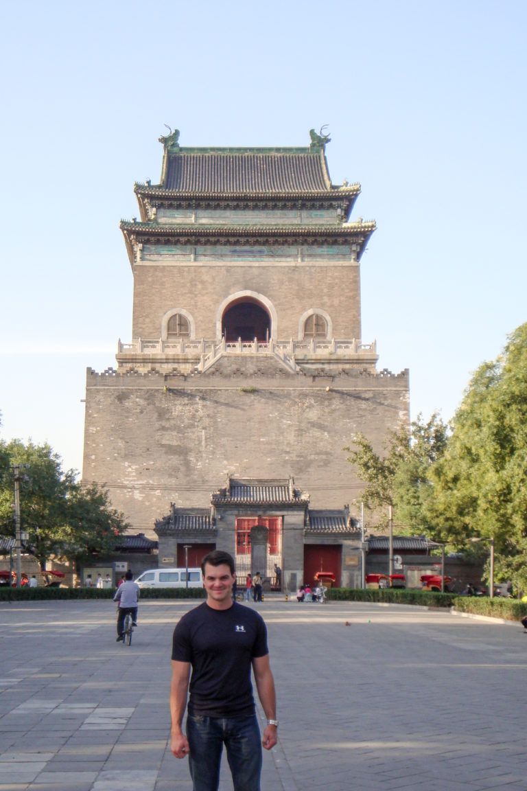 Beijing Drum Tower seen from the forecourt, showing its high gray-brick base and tall timber pavilion with a dark tiled roof.