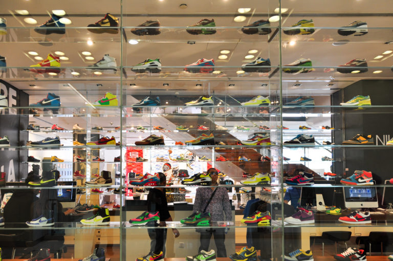 Brightly lit Beijing sneaker shop with rows of colorful sneakers displayed on glass shelves.