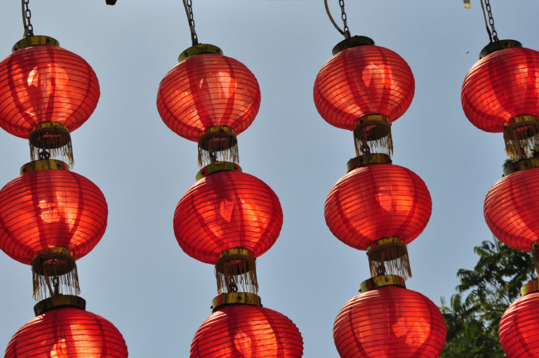 Vertical columns of traditional red lanterns with gold trim and tassels hanging outdoors.