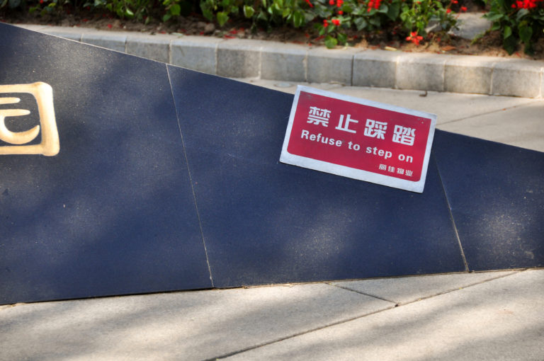 Red-and-white bilingual warning sign reading “Refuse to step on” placed on a dark platform.