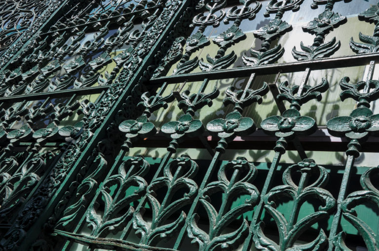 Green-painted floral cast-metal screen on a historic commercial building in Beijing, with raised flowers and leaves across the grille.