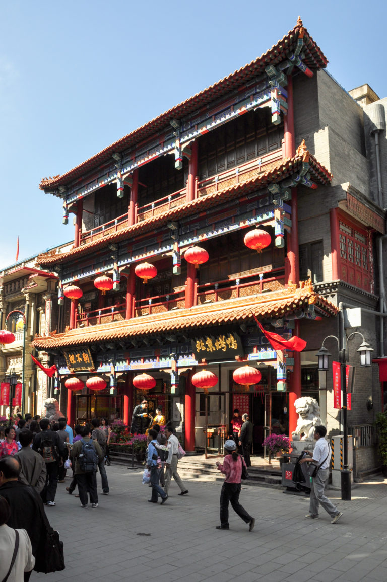 Ornate multi-story Chinese-style commercial building with tiled eaves and rows of red lanterns on the facade.