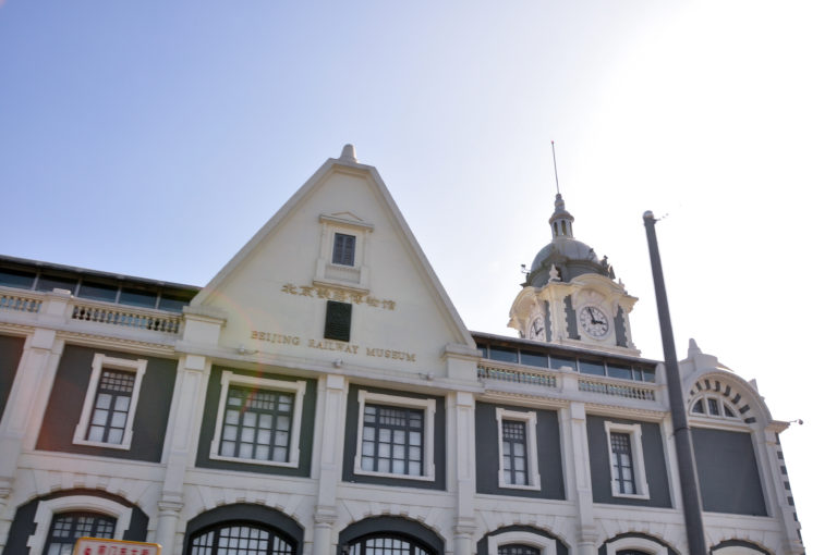Pale European-style facade of the Beijing Railway Museum, formerly Zhengyangmen East Railway Station, with arched openings, a gable, and a clock tower.
